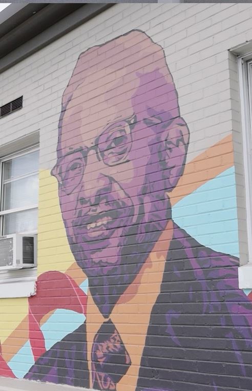 Mural of an African American man on a wall near a busy street