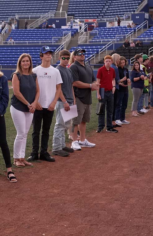 Apprentices, Family Members and Employers being recognized on a baseball field.